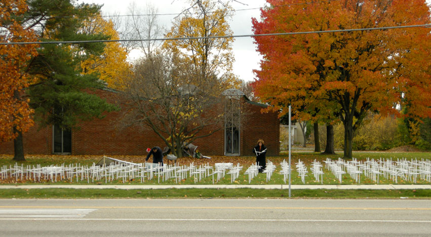 Man and woman planting rows of crosses on church lawn